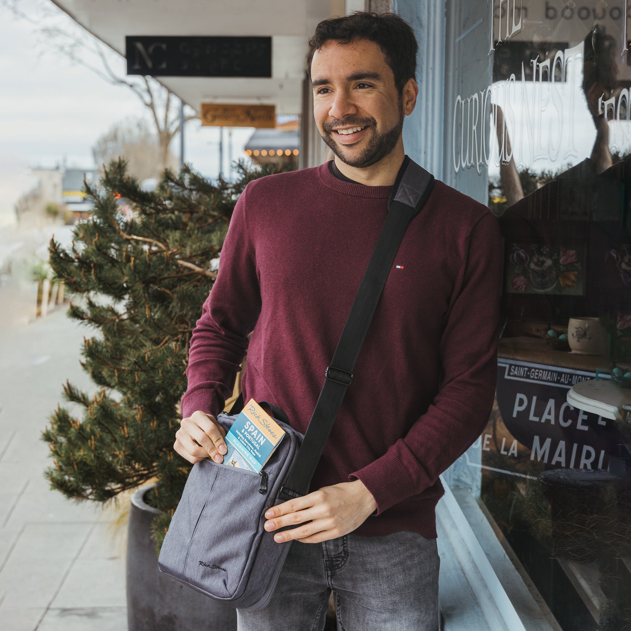 man wearing a travel crossbody bag in heather gray heather navy